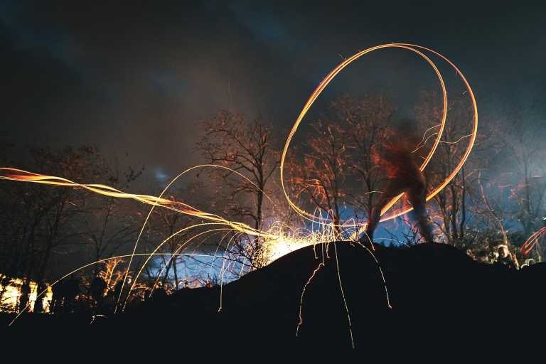 Teilnehmer schleudert bei der Schieweschlawe in Diefenthal eine glühende Holzscheibe, deren Funken und Lichtspuren den Nachthimmel erhellen.