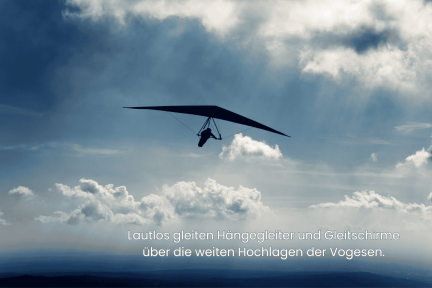 Hängegleiter gleitet lautlos über die Hochlagen der Vogesen unter wolkigem Himmel.