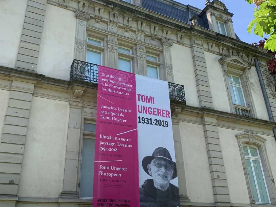 Blick auf die Fassade des Tomi-Ungerer-Museums mit einer Fahne mit dem Bild des Künstlers