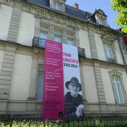 Blick auf die Fassade des Tomi-Ungerer-Museums mit einer Fahne mit dem Bild des Künstlers