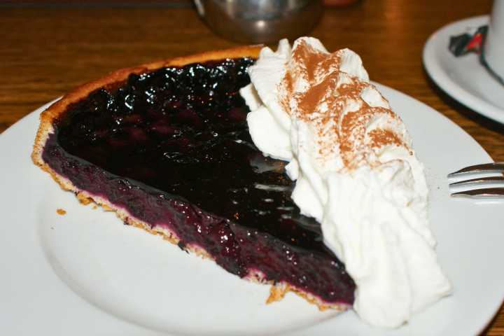 Tarte aux myrtilles mit Sahne auf einem Teller – klassischer Heidelbeerkuchen aus den Vogesen